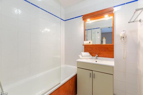 a bathroom with a tub and a sink and a mirror at Appart'City Classic Limoges in Limoges