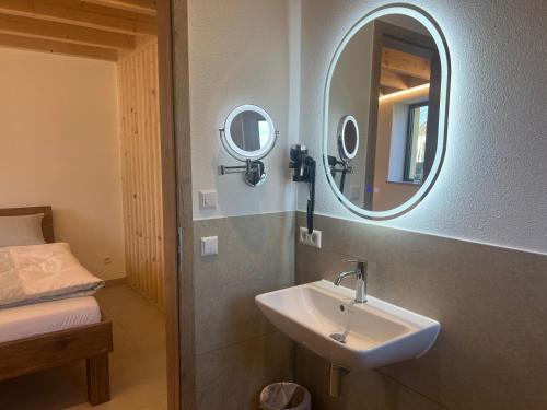 a bathroom with a sink and a mirror and a bed at Ferienwohnung, 1-Zimmer, 1-3 Personen, 31 qm, mit Balkon, in ruhige Lage, direkt an der Aach in Singen