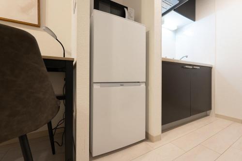 Cette chambre comprend un réfrigérateur blanc et un bureau. dans l'établissement Ferio Kamata, à Tokyo