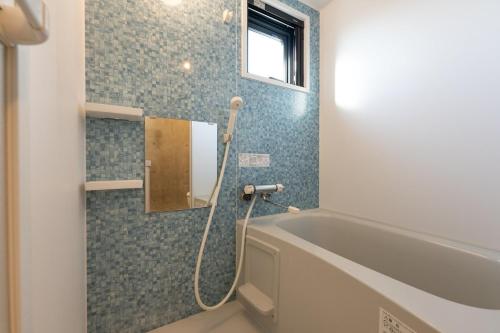 a bathroom with a bath tub and a window at Ferio Kamata in Tokyo