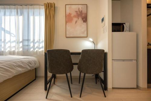 - une chambre avec un bureau avec deux chaises et un lit dans l'établissement Ferio Kamata, à Tokyo