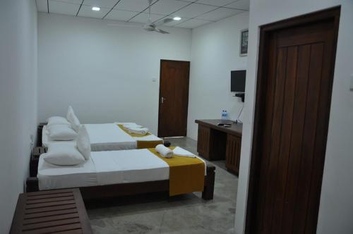 a bedroom with a bed and a sink and a television at Trinco Rest House in Trincomalee