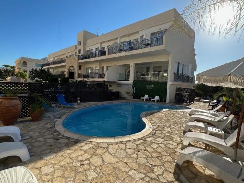 a house with a swimming pool in front of a building at King's Holiday Apartments in Paphos