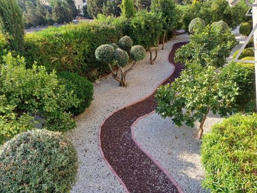 a garden with bushes and trees and a walkway at King's Holiday Apartments in Paphos City