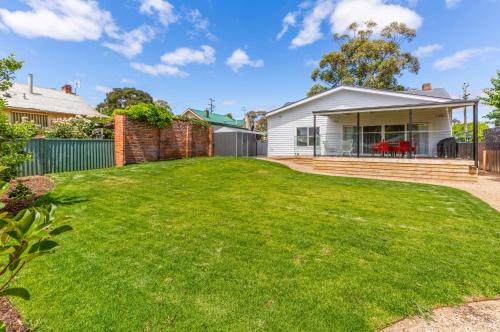 a house with a large lawn in front of it at COSY RETREAT ON FOREST --- Offering 3 Comfortable Bedrooms - Sleeps Up to 6 - Please Note - If Booking for 5 or more guests all 3 rooms will be required in Bendigo