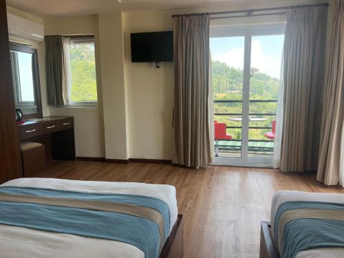 a hotel room with two beds and a balcony at Nagarkot Resort PVt. Ltd in Nagarkot