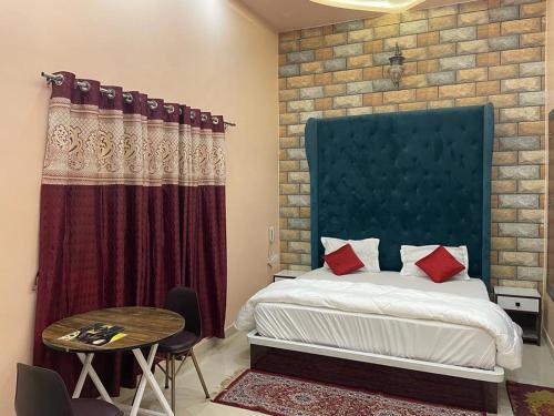a bedroom with a bed with a blue headboard and a table at Hotel Ankit Near Assi Ghat in Varanasi