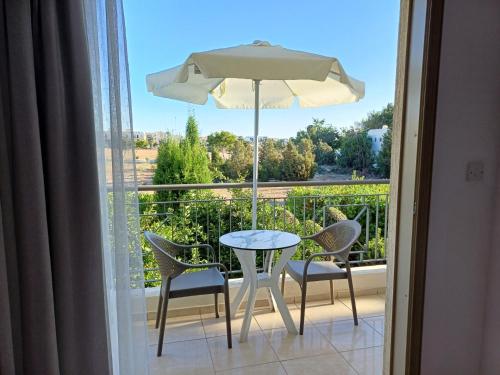 a table and chairs and an umbrella on a balcony at King's Holiday Apartments in Paphos City