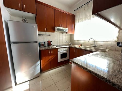 a kitchen with wooden cabinets and a refrigerator at King's Holiday Apartments in Paphos City