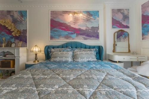 a bedroom with a blue bed and paintings on the walls at Súp Lơ House (Broccoli's House) in Da Lat
