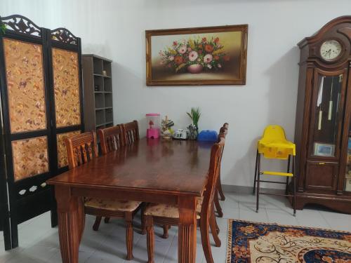 a dining room with a wooden table and a clock at Hulu Yam Musliim Homestay in Batang Kali