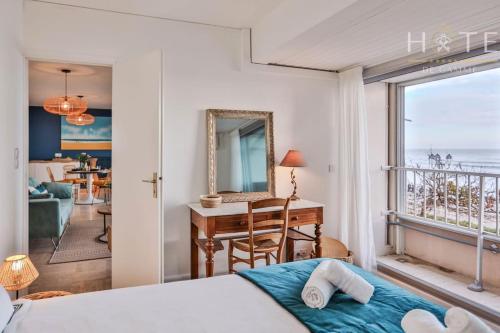 a bedroom with a bed and a desk and a balcony at Appartement central, vue mer époustouflante. in Les Sables-d'Olonne
