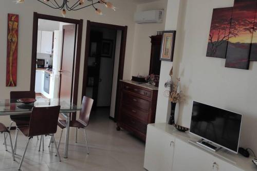 een woonkamer met een eettafel en een televisie bij Lella's Home in Quartu SantʼElena
