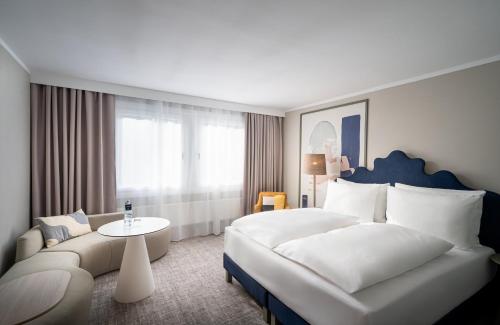 een hotelkamer met een groot bed en een bank bij voco Vienna Prater, an IHG Hotel in Wenen