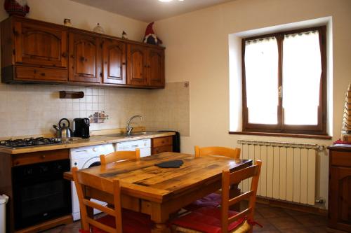 uma cozinha com uma mesa de madeira com cadeiras e um lavatório em Chalet Abetone in Tuscany em Abetone