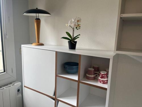 une étagère blanche avec une plante en pot et une lampe dans l'établissement Studio - Disneyland/Paris, à Bussy-Saint-Georges