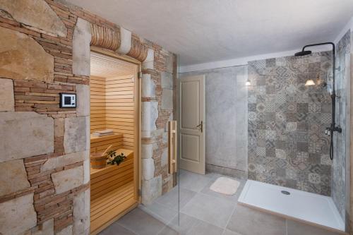 a bathroom with a walk in shower next to a stone wall at Villa Malini with Pool, Sauna and Fenced Garden in Labin
