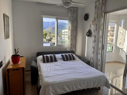 a bedroom with a bed and a large window at Piso a pie de playa con piscina y vistas al mar in Benicàssim