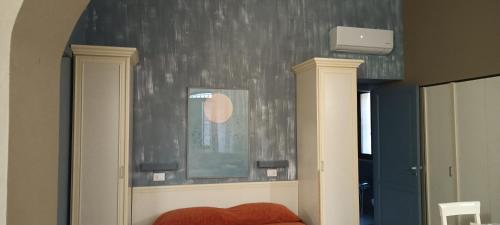 a bedroom with a wall with a mirror and a red couch at Le Plejadi in Castellammare del Golfo