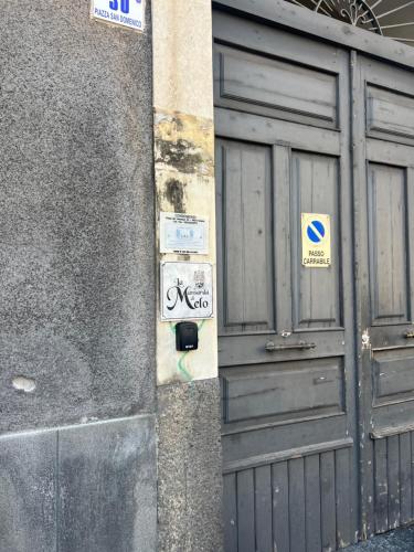 a pole with signs on it next to a door at La mansarda di melo in Catania