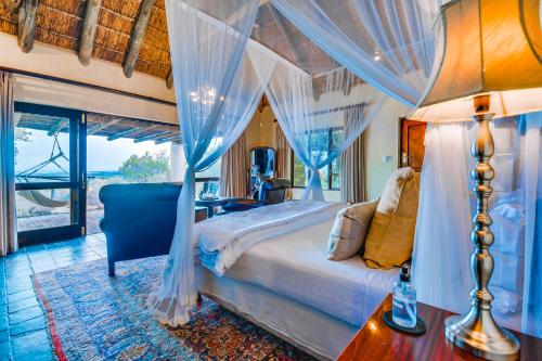 a bedroom with a canopy bed and a window at Hitgeheim Country Lodge in Addo