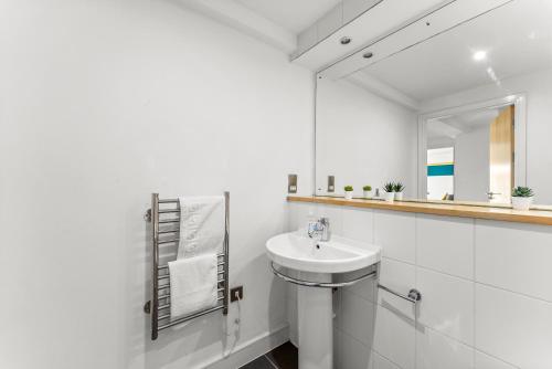 a white bathroom with a sink and a mirror at Enchanting Bristol Abode -Sleeps 6 with Balcony! in Bristol
