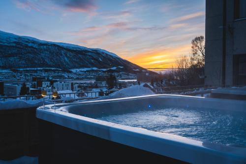 een hot tub met een zonsondergang op de achtergrond bij Enter St Elisabeth Hotel & Spa in Tromsø
