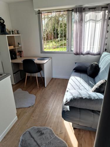 a living room with a couch and a desk and a window at Studio proche du CHU in Nîmes