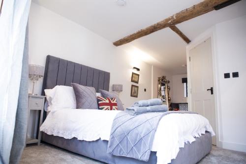 a bedroom with a bed with a large gray headboard at The Penthouse at Mercers Croft in Stratford-upon-Avon