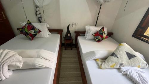two beds in a room with white sheets and pillows at Sophie Homestay in Moshi
