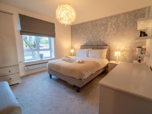 a bedroom with a bed and a window and a chandelier at Pass the Keys Super luxurious 2 bedroom apartment in Nottingham
