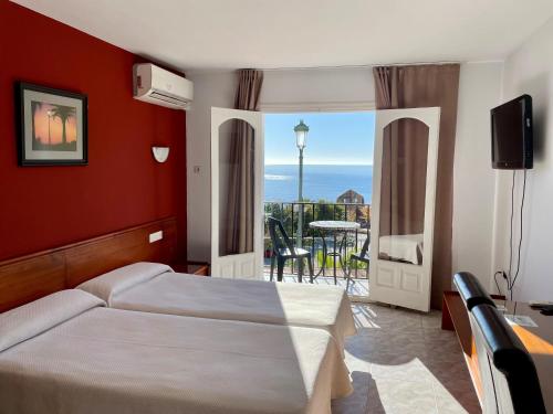 1 dormitorio con cama y vistas al océano en Apartamentos Balcón de Maro, en Maro