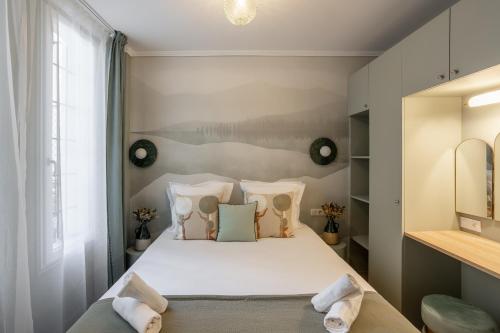una camera da letto con letto, lenzuola e cuscini bianchi di The Liberty Green Suite a Parigi