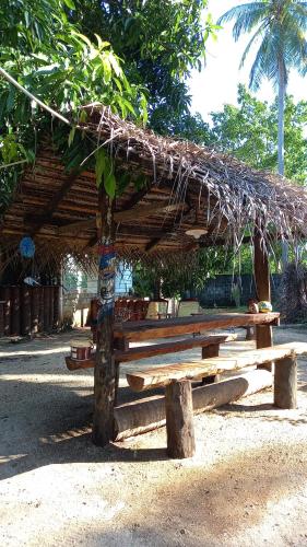 a wooden picnic table with a straw roof at Elena Garden Resort and Restaurant in Trincomalee
