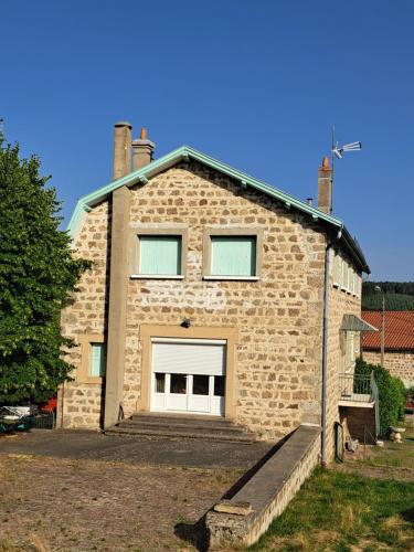 a large brick building with a large garage at Chez Patrice et Marieline in Usson-en-Forez