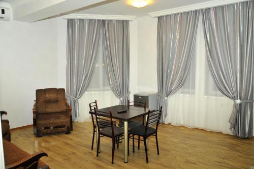 una sala da pranzo con tavolo, sedie e tende di Alma-Ata Hotel a Borjomi