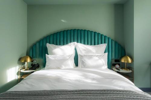 a bed with a green headboard and white pillows at Khedi Hotel by Ginza Project in Tbilisi City