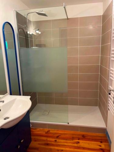 une douche avec une porte vitrée à côté d'un lavabo dans l'établissement GS2 DUPLEX 4 PERS TERRASSE 5mn LUZ 15 mn ARDIDEN, à Sassis