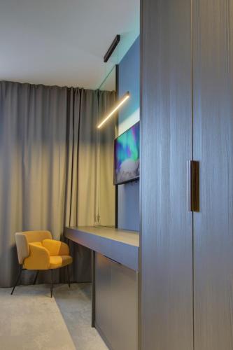 a room with a desk and a tv and a yellow chair at Avenue21 in Zagreb