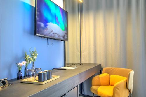 a room with a desk with a television and a yellow chair at Avenue21 in Zagreb
