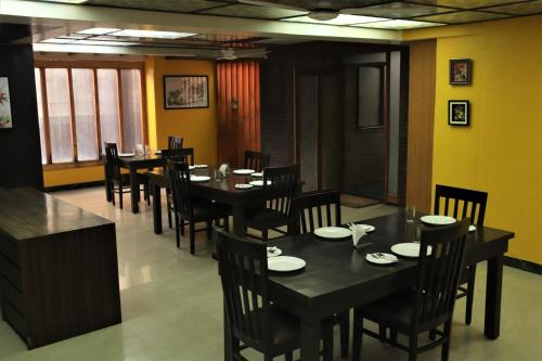 a restaurant with black tables and chairs and yellow walls at Hotel Serene Viman Nagar in Pune
