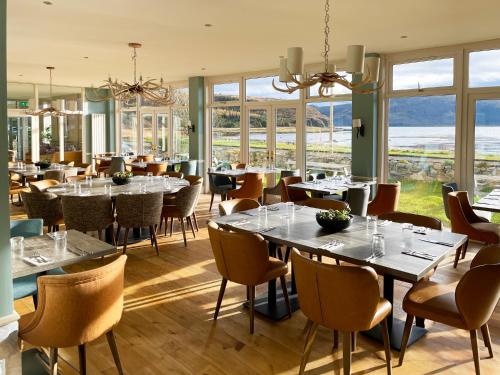 un restaurante con mesas, sillas y ventanas en Balmacara Hotel, en Kyle of Lochalsh