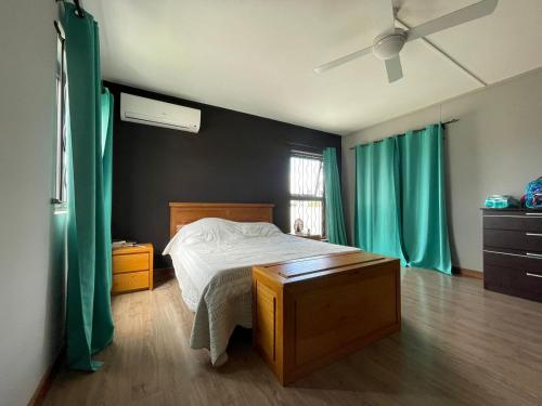 1 dormitorio con 1 cama con cortinas verdes y ventana en Villa vue 1 C.A.M en Albion