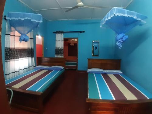 2 camas en una habitación con paredes azules en Amila Guest, en Trincomalee