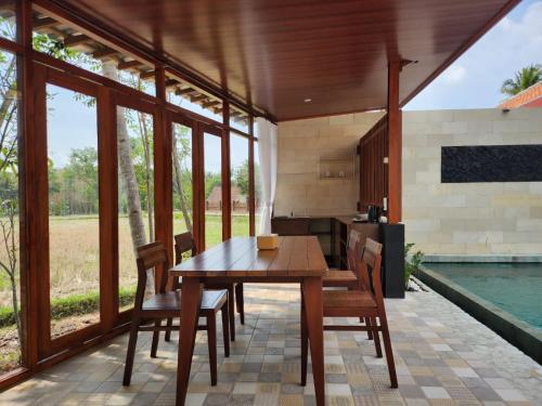 eine Küche und ein Esszimmer mit einem Holztisch und Stühlen in der Unterkunft Nalendro Villa Borobudur in Borobudur