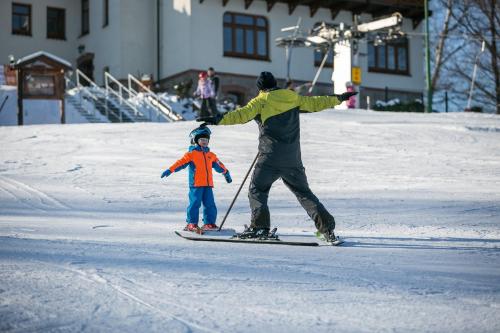 Ein Mann und ein Kind auf Skiern im Schnee in der Unterkunft Treehouse Karpacz in Karpacz