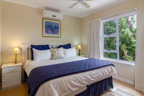 a bedroom with a bed with a blue comforter and a window at Dunwerkin Self Catering in Kenton on Sea