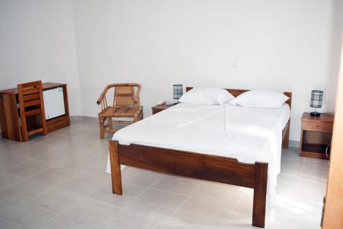 um quarto com uma cama, uma mesa e uma cadeira em Residencial Aeroporto em São Tomé