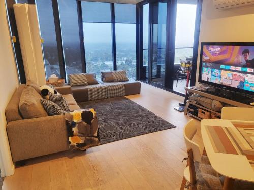 a living room with a dog sitting on a couch in front of a television at Modern&cozy life in Sky Garden 5min from station in Glen Waverley