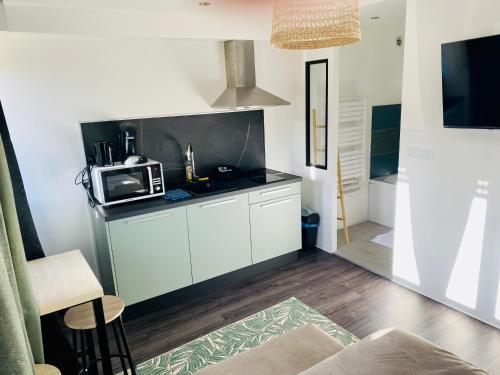 une cuisine avec des armoires blanches et un micro-ondes dans l'établissement L'Ancillon Metz Gare Wifi Un-Séjour-à-Part, à Metz